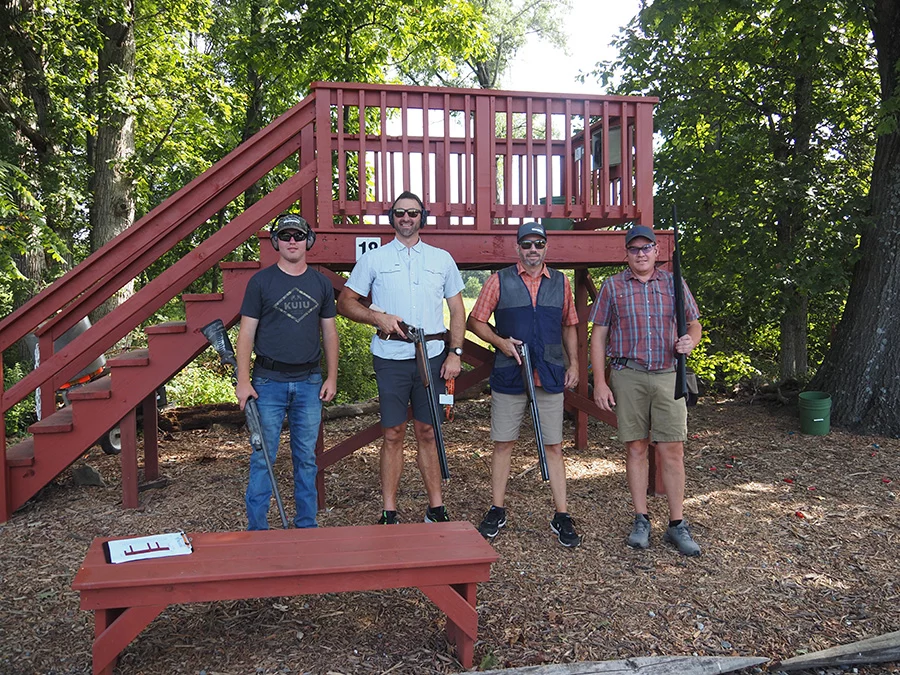 Men standing outdoors holding rifles.