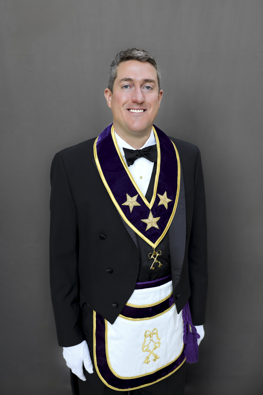 Smiling man with short hair dressed in Masonic Grand Lodge Officer attire.
