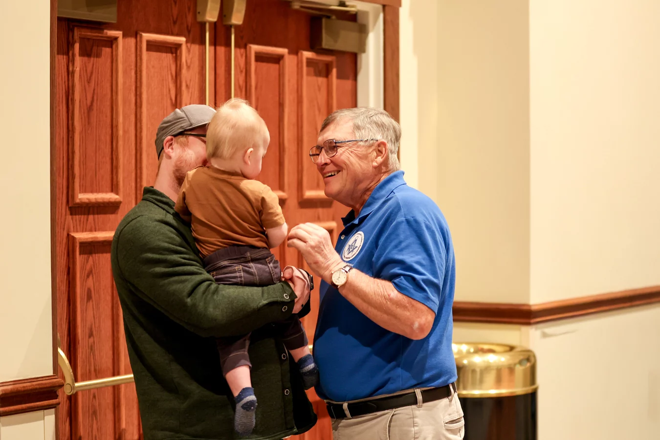 1W8A4944 Man smiling at dad holding his toddler.