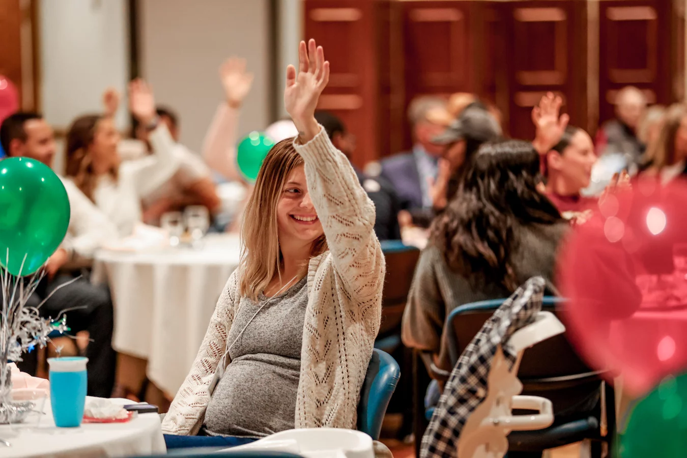 1W8A4951 Smiling pregnant woman raising her hand.