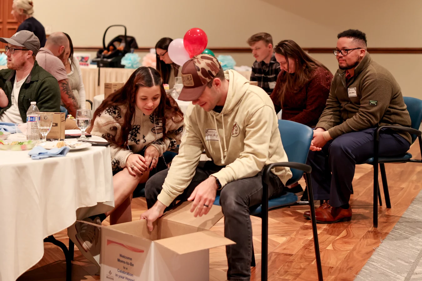 1W8A4972 Couple opening a large box while sitting at table.