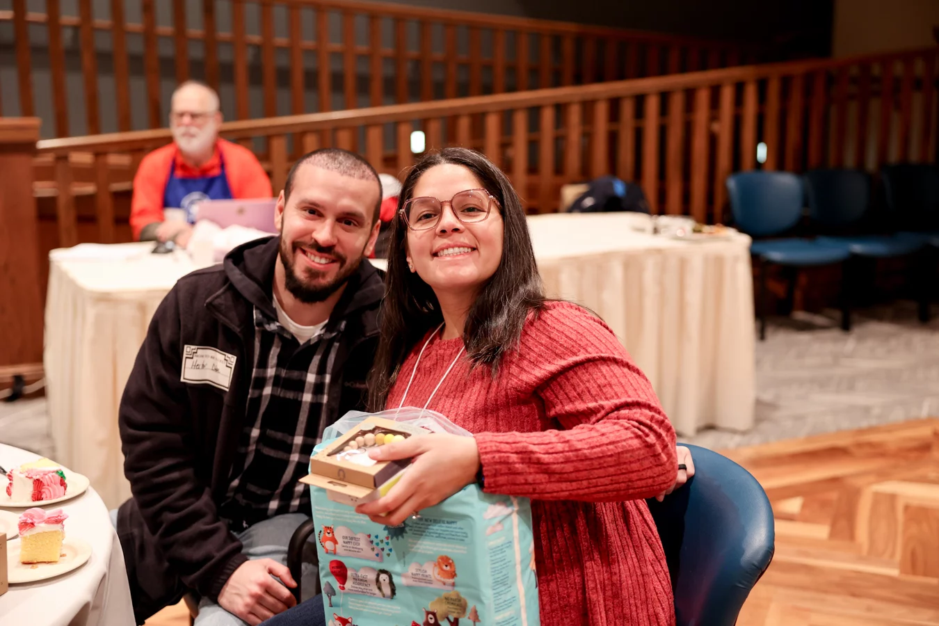 1W8A4977 Smiling couple holding baby toys while seated at table.