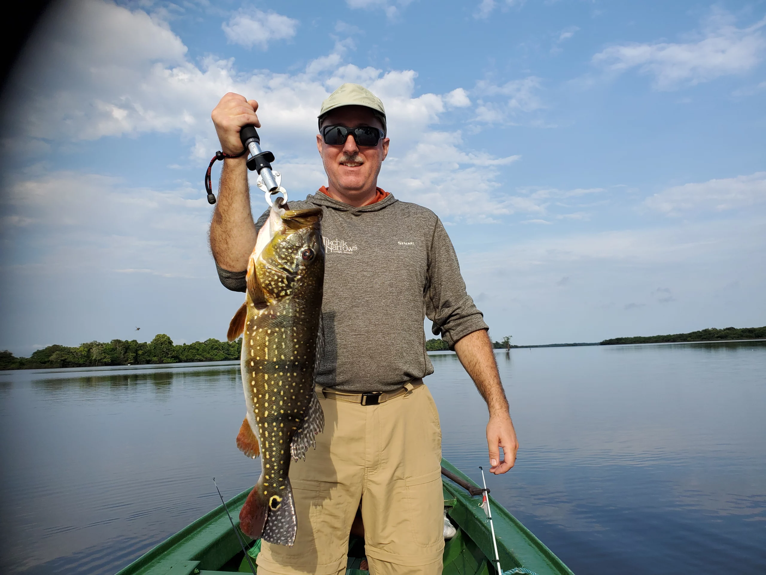 Man standing on boat holding out a large fish.