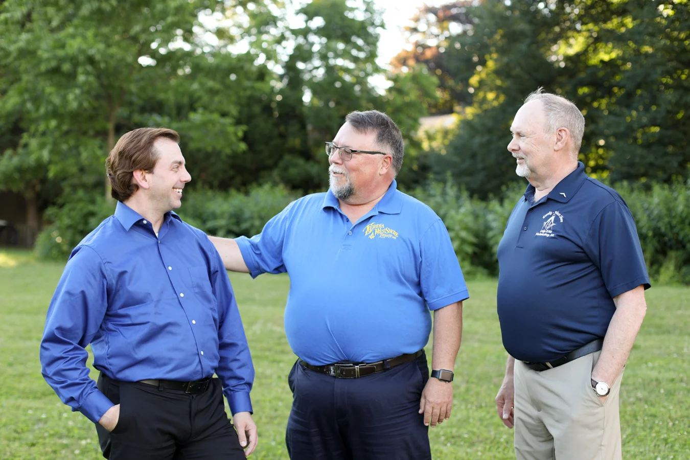 Smiling men standing outdoors together.