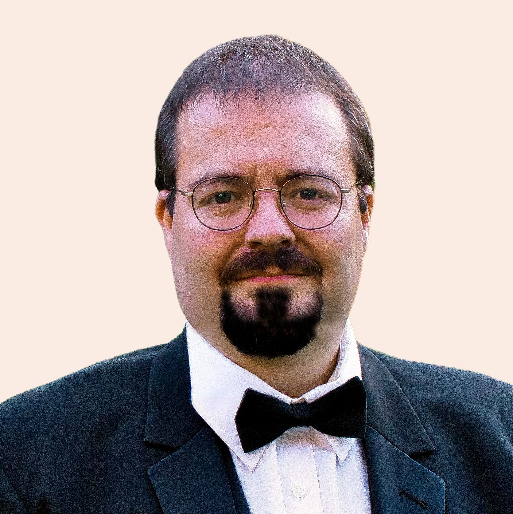 Man in a suit and bow tie with short, dark hair, goatee and glasses.