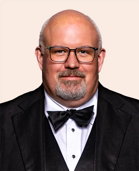 Man with short grey hair and goatee wearing suit and bow tie.