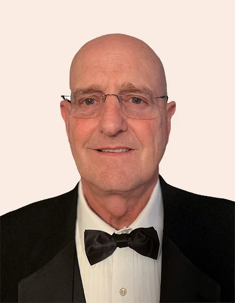 Smiling man wearing glasses, suit and bow tie.
