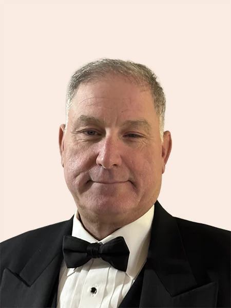 Smiling man with short grey hair, wearing suit and bow tie.