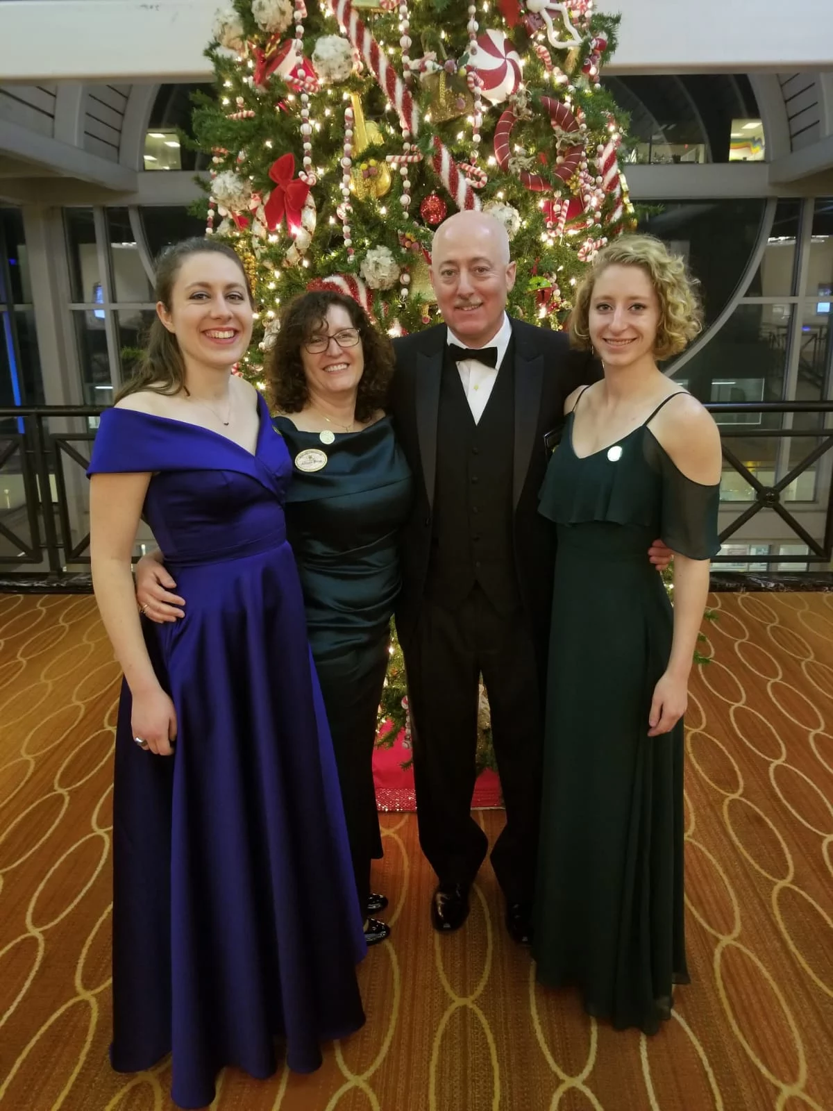 Grand Master Robert Brink and his wife posed in front of a Christmas tree with two young women.