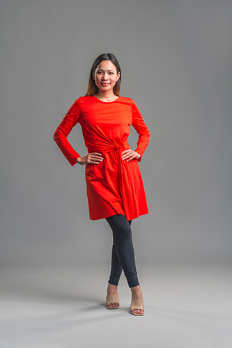 Smiling woman in red, knee-length dress and grey leggings.