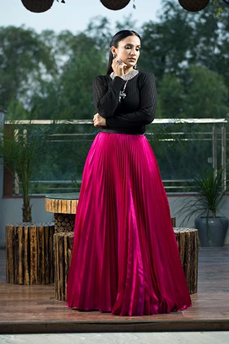 Woman in black long sleeve dress top and full length pink skirt.
