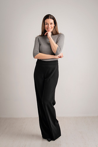 Woman in grey top and black dress pants.