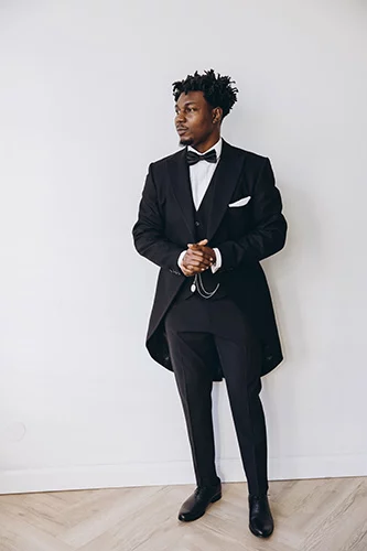 Man in long-tailed jacket, black dress pants and bow tie.