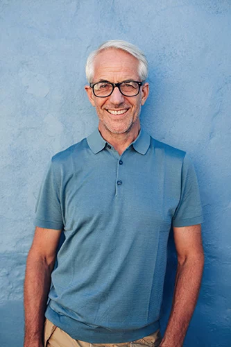 Smiling man wearing blue polo shirt and tan pants.