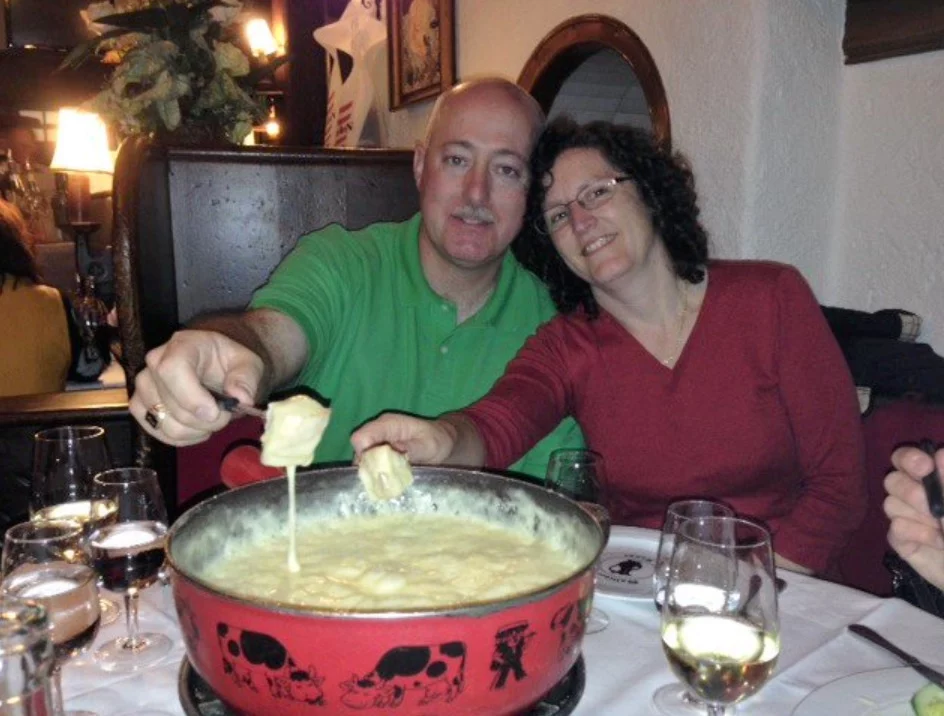 Grand Master Robert Brink and his wife dipping bread into fondue cheese,