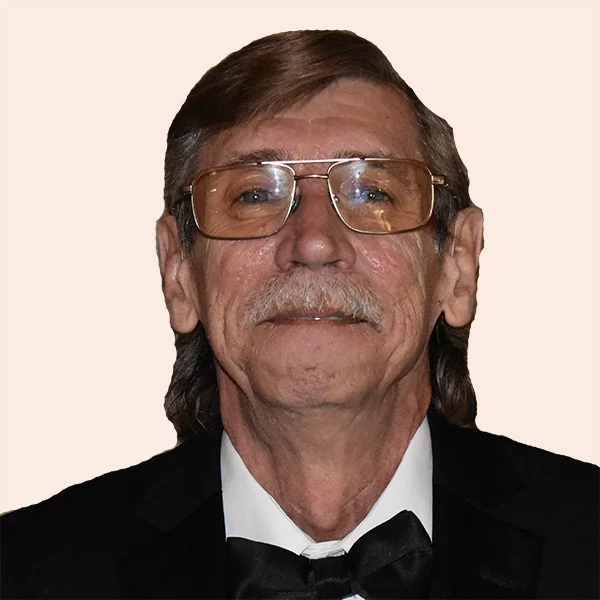 Smiling man with glasses, long hair and mustache.