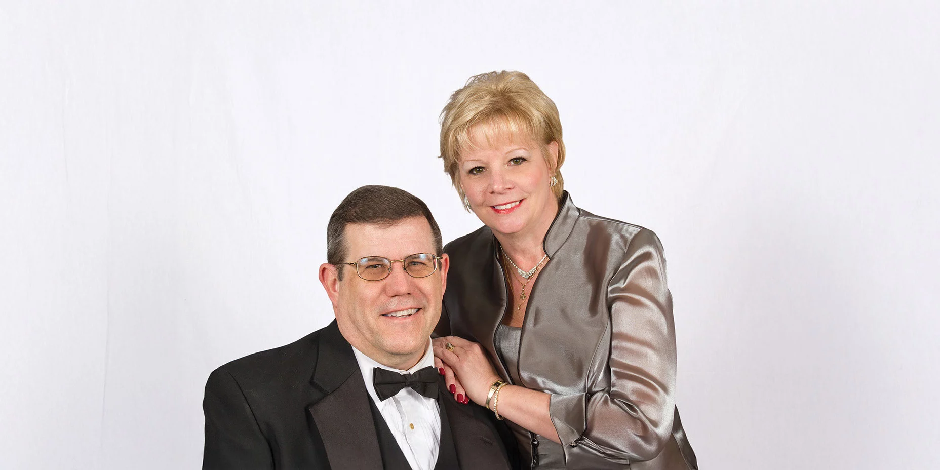Smiling man and woman posed together dressed in formal attire.