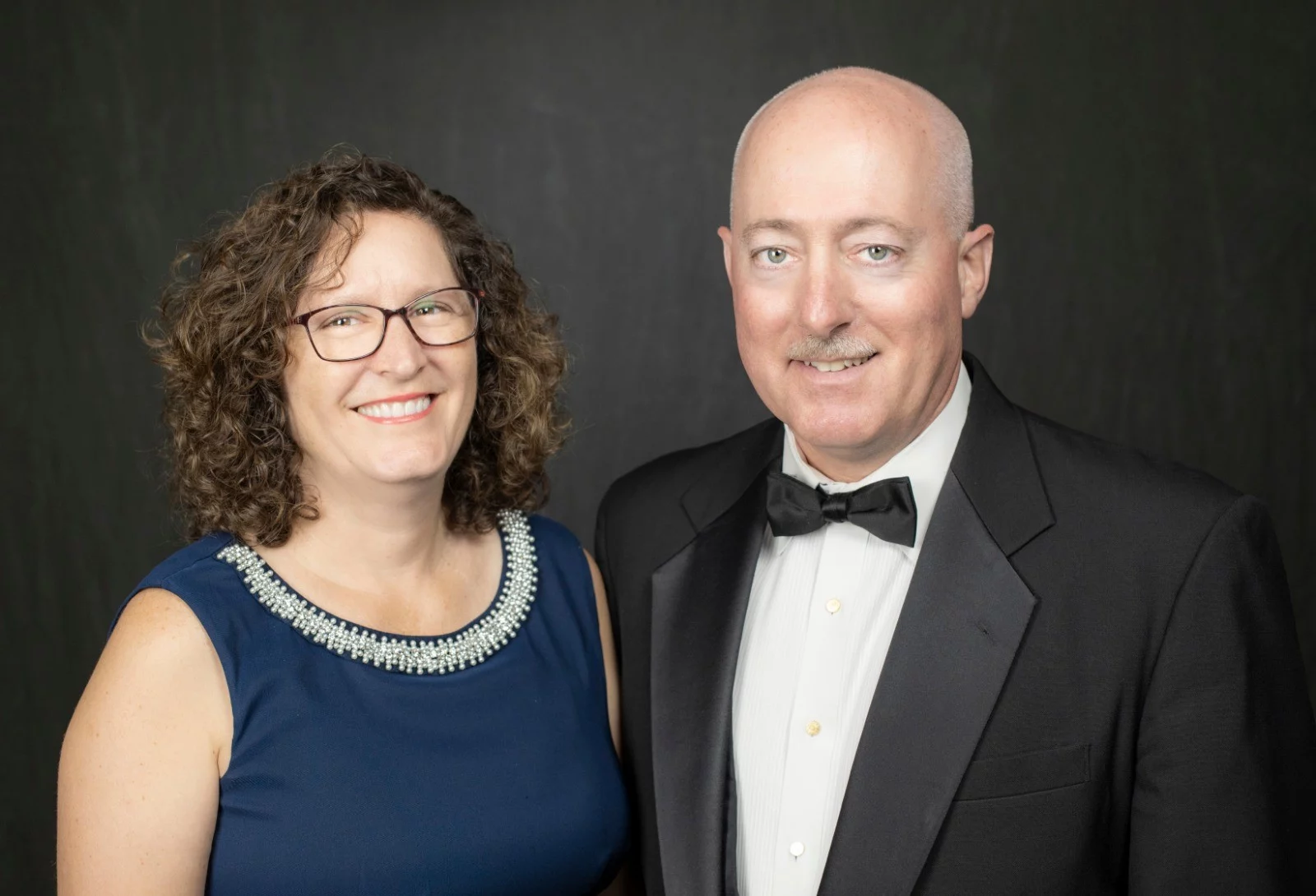Grand Master Robert Brink and his wife smiling while posed together dressed in formal attire.