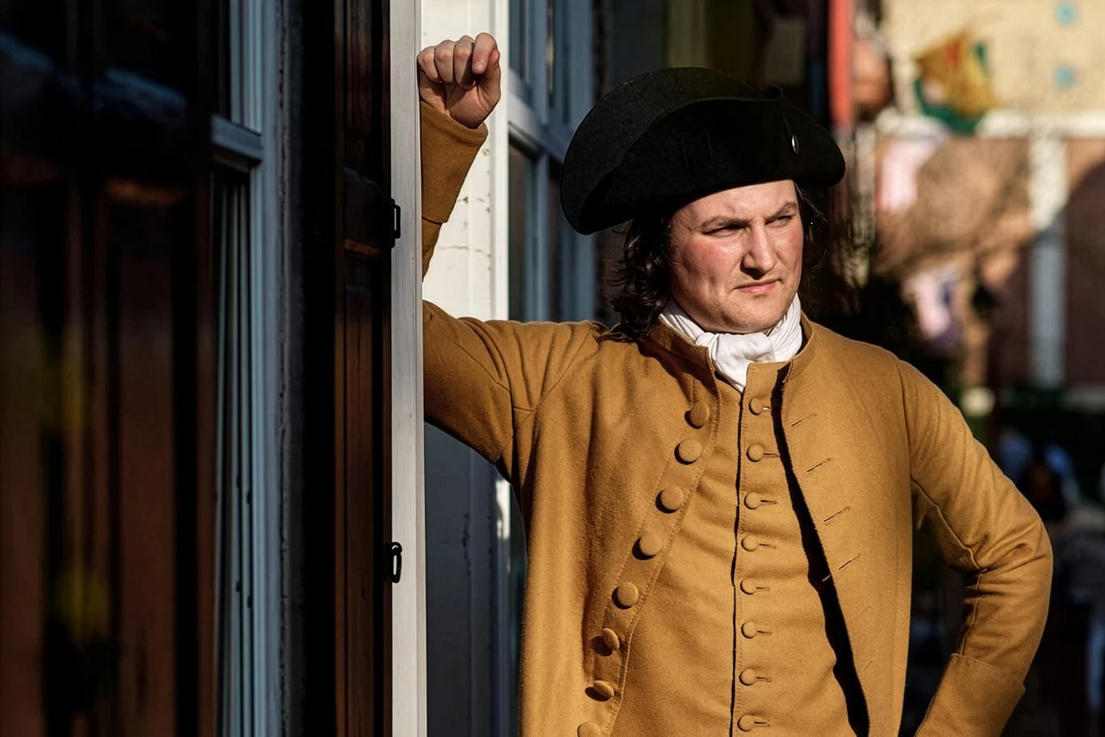 Man dressed in revolutionary war costume leaning against a wall.