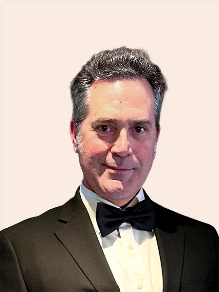 Smiling man with short grey hair and side burns wearing suit and bow tie.