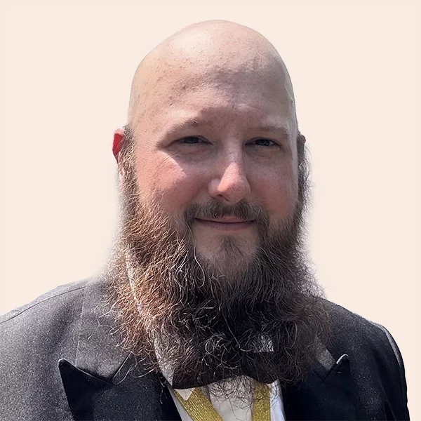 Smiling man with long beard wearing a suit and bow tie.