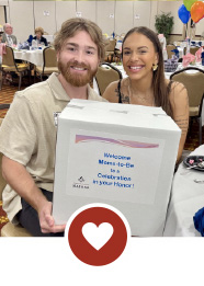 Smiling couple holding box together with heart icon.