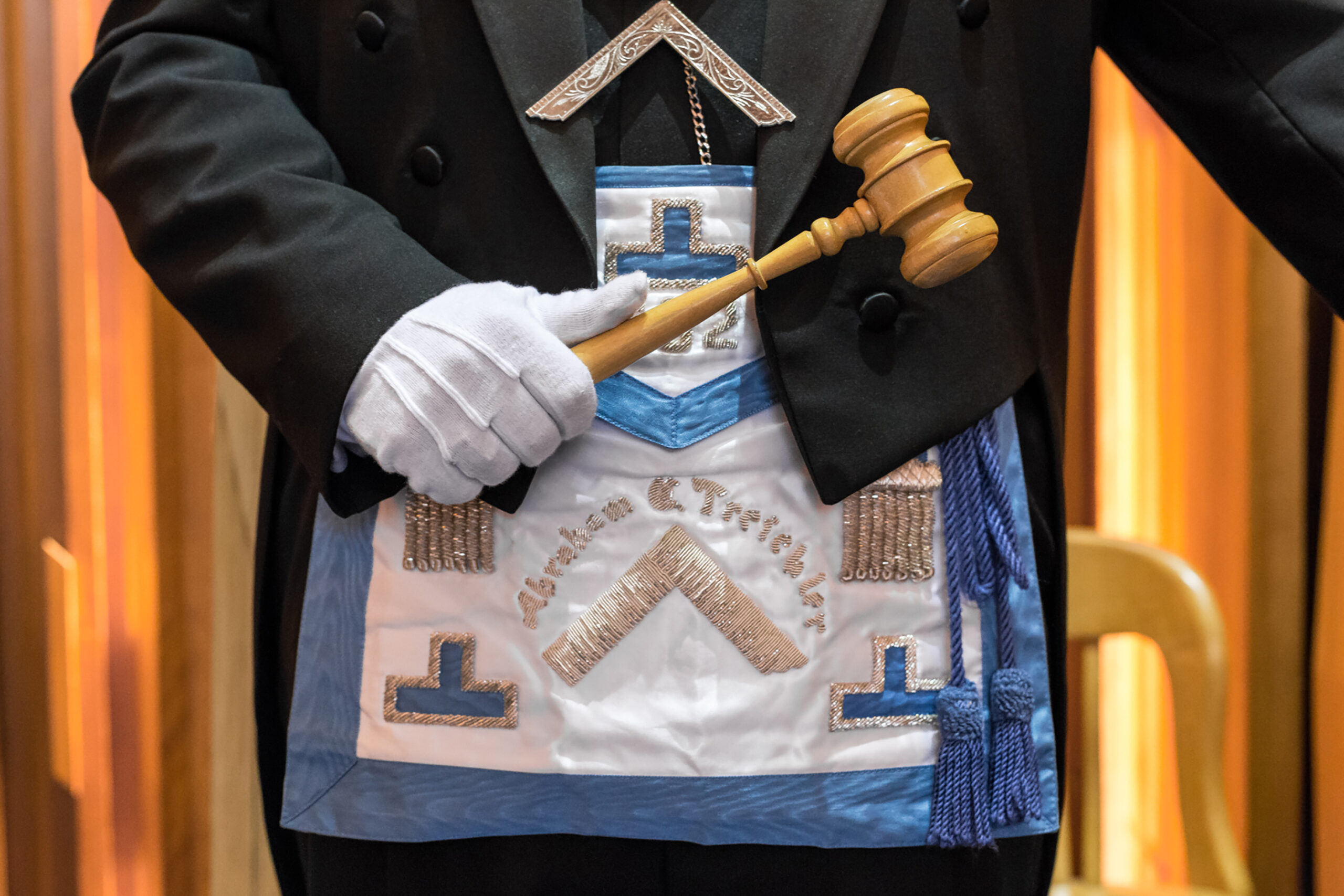 Closeup of man in Masonic dress holding a wooden mallet.