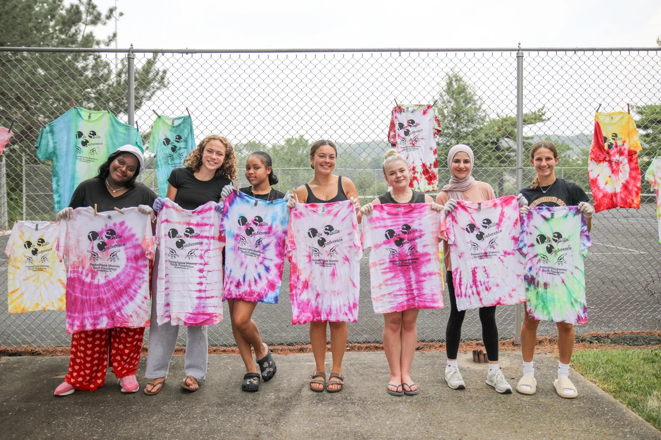 Group of teenage girls holding up tie dyed shirts.