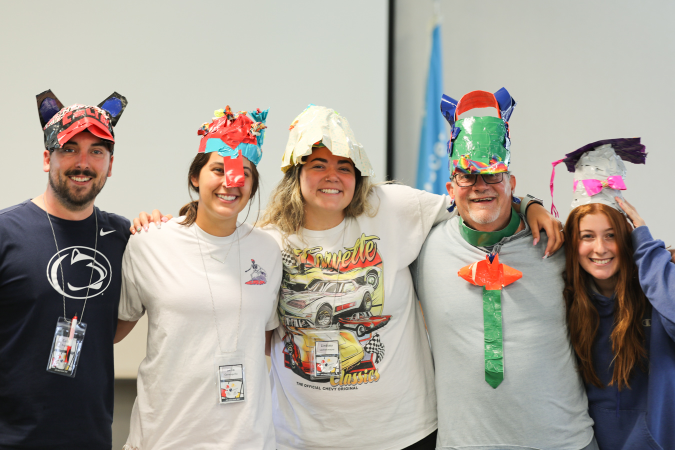 Smiling group of adult volunteers wearing hats made from colorful duct tape.