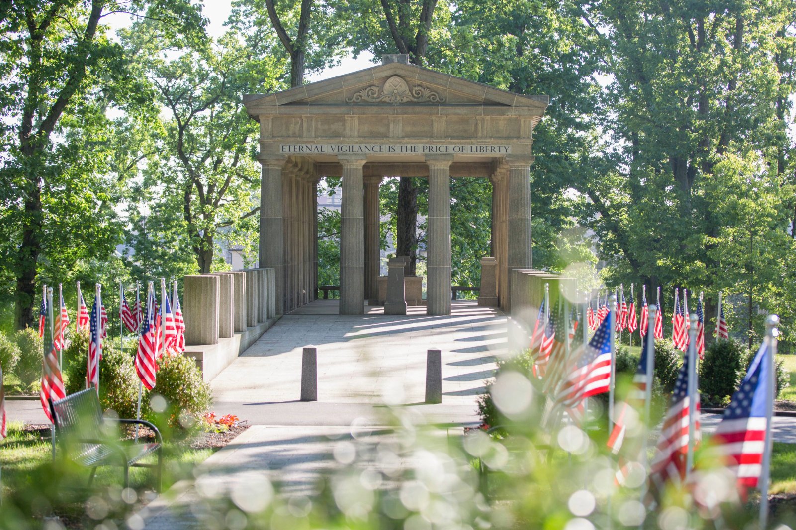 The Veterans grove at Masonic Village at Elizabethtown, a flag-lined bath leads up to a loggia surrounded by trees.