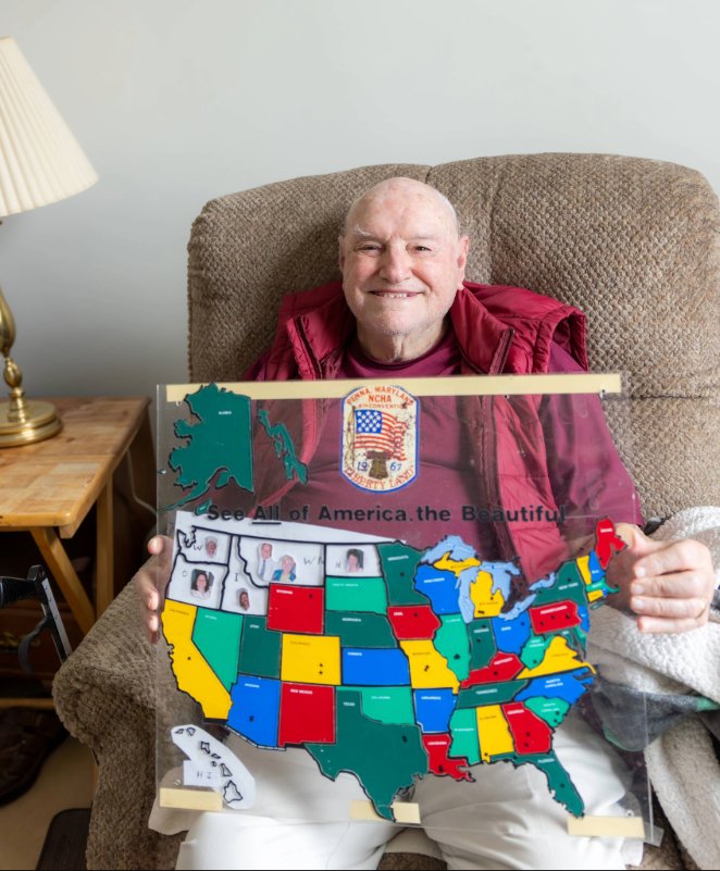 Smiling senior man holding up map of the United States.