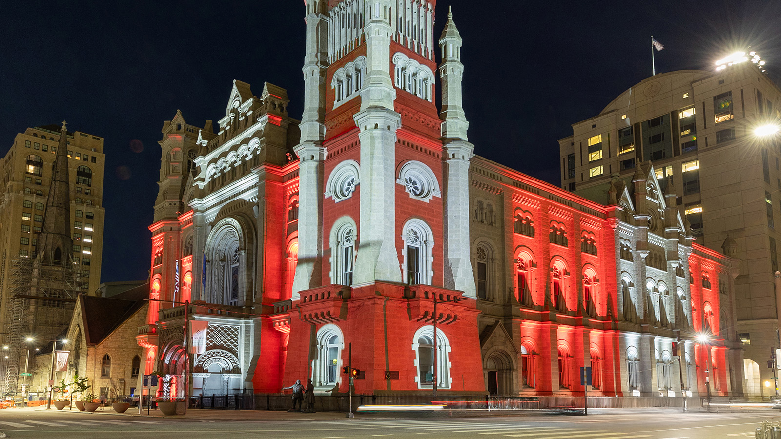The Masonic Temple, Library and Museum illuminated at night with red and white lights.