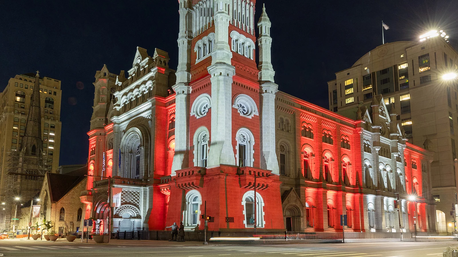 The Masonic Temple, Library and Museum illuminated at night with red and white lights.