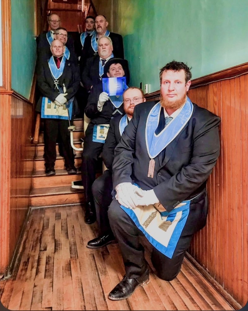 Men in Masonic dress posed together in stairwell.