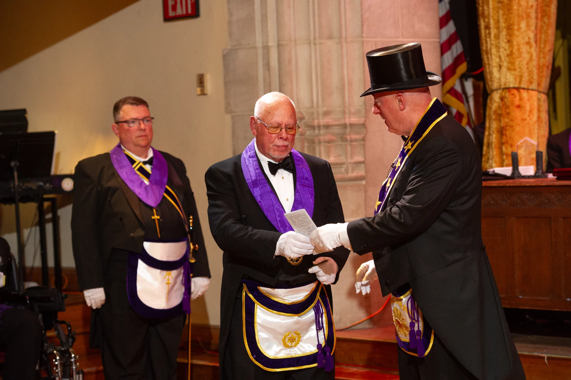 Grand Master Robert Brink handing paper to a man on stage.