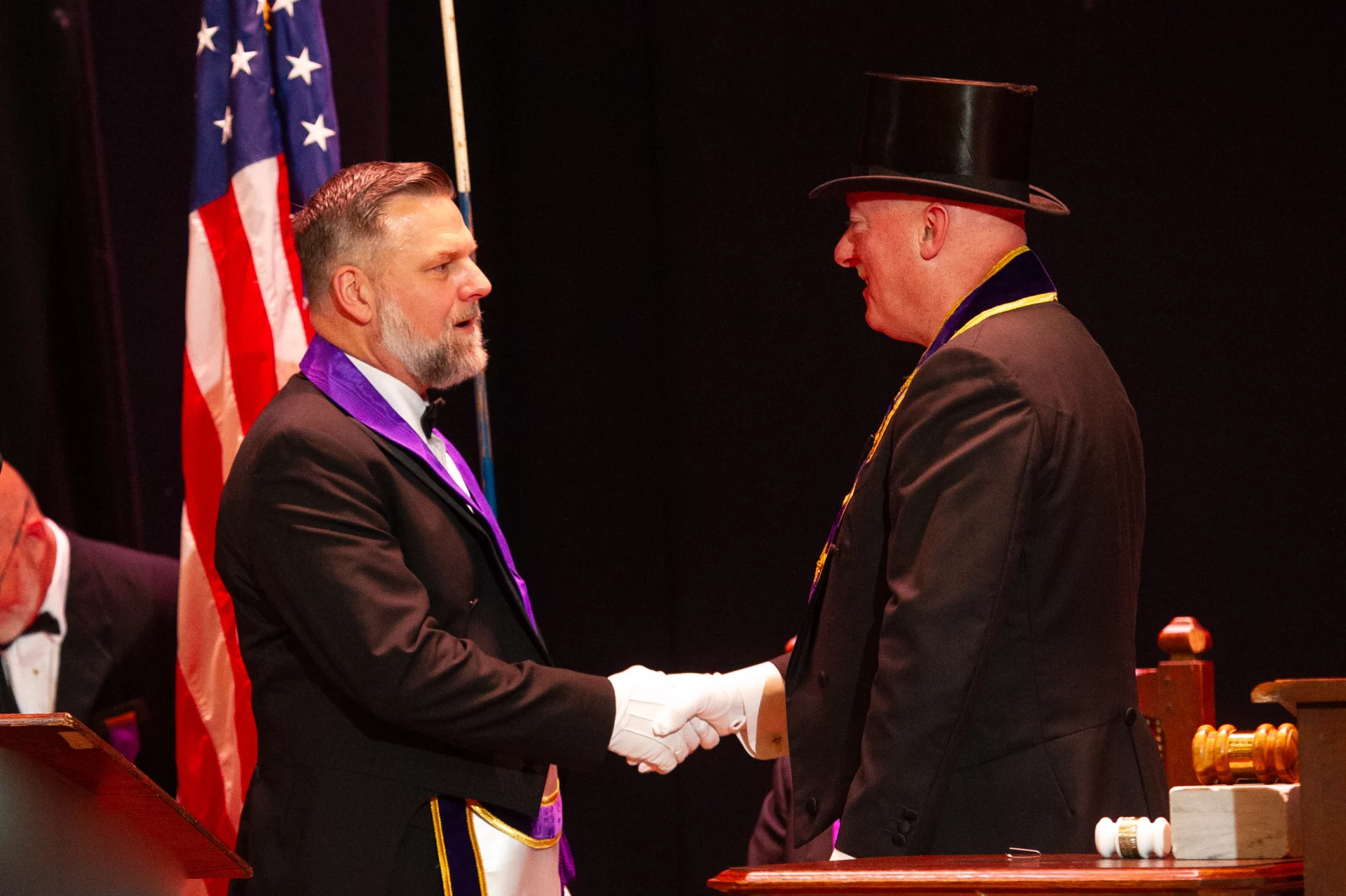 Man shaking hands with Grand Master Robert Brink on stage.