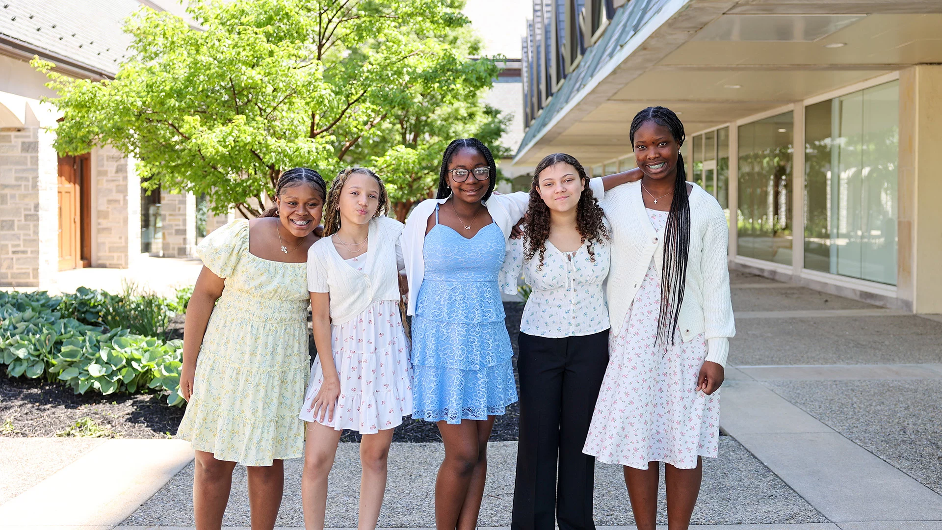 Smiling group of girls dressed in formal attire standing outdoors.