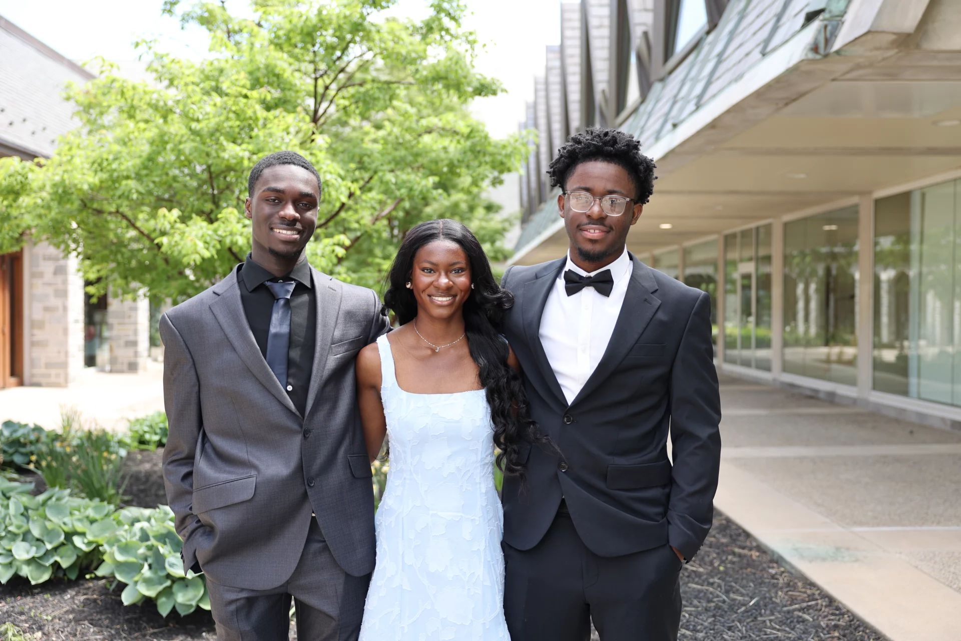 Smiling group of teens dressed in formal attire standing outdoors.