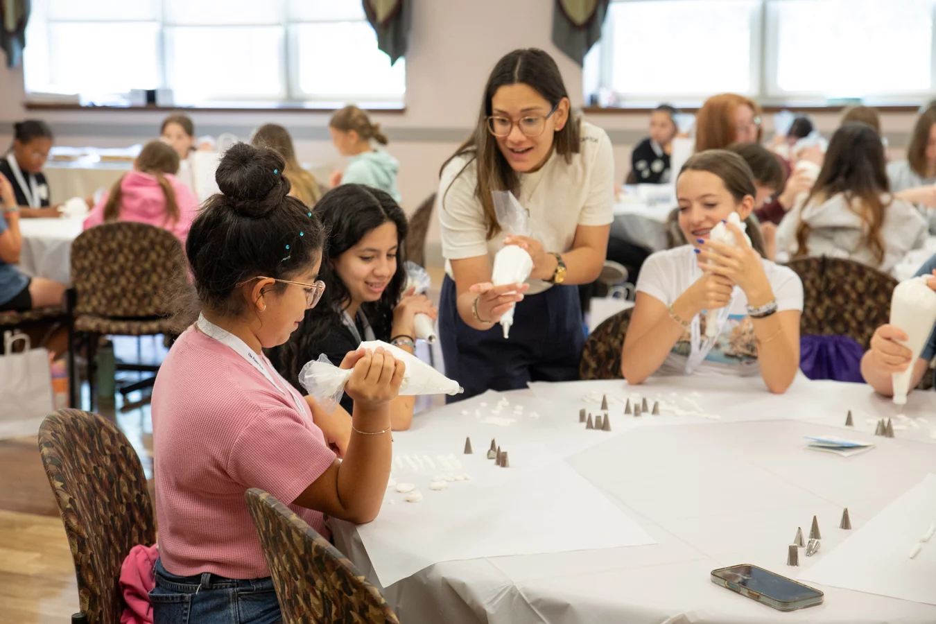 2V9A5223 Youth group leader working with smiling group of girls working with icing.