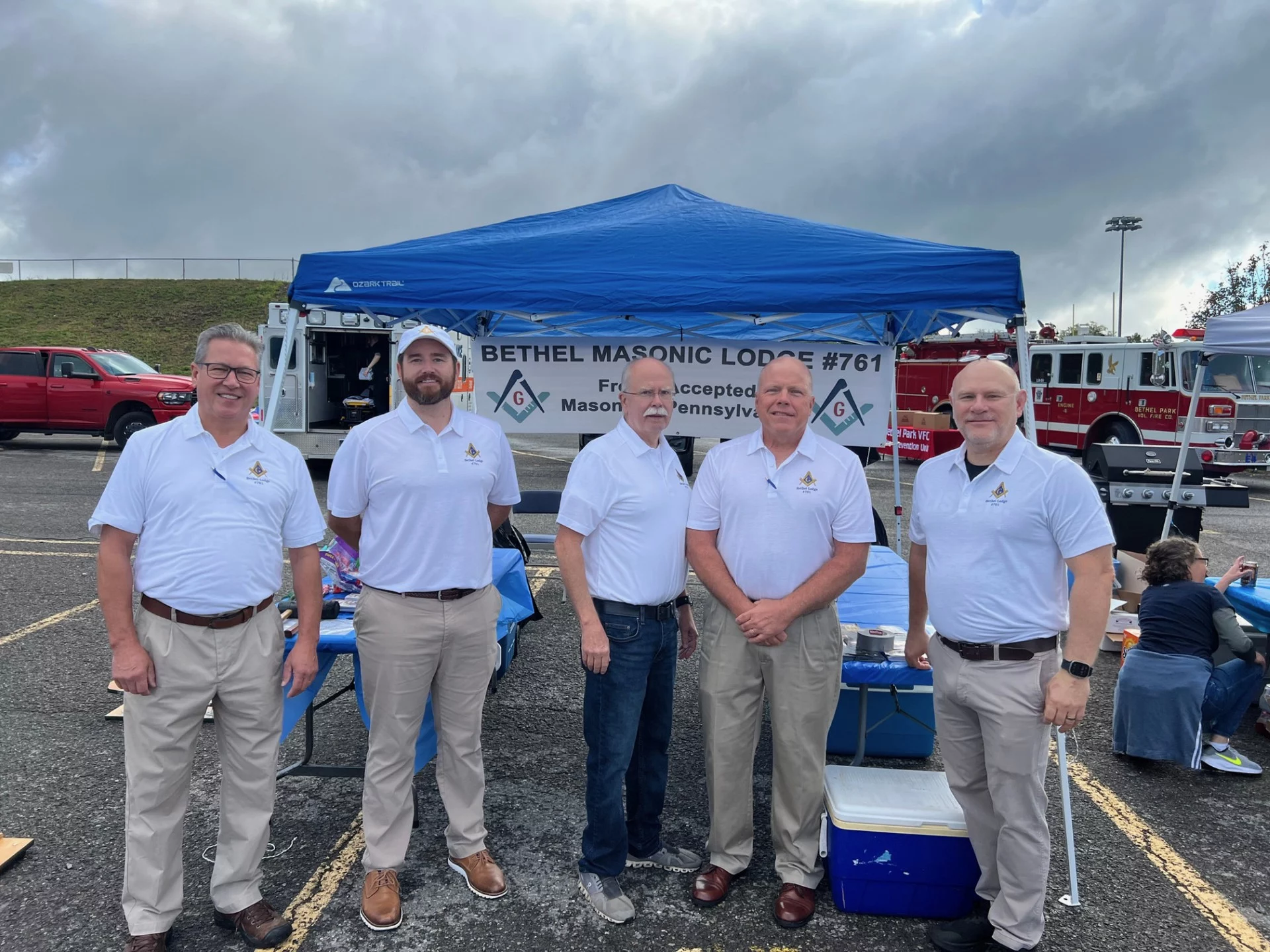 Smiling group of men in white masonic polos standing in front of a tent for Bethel Masonic Lodge #761.