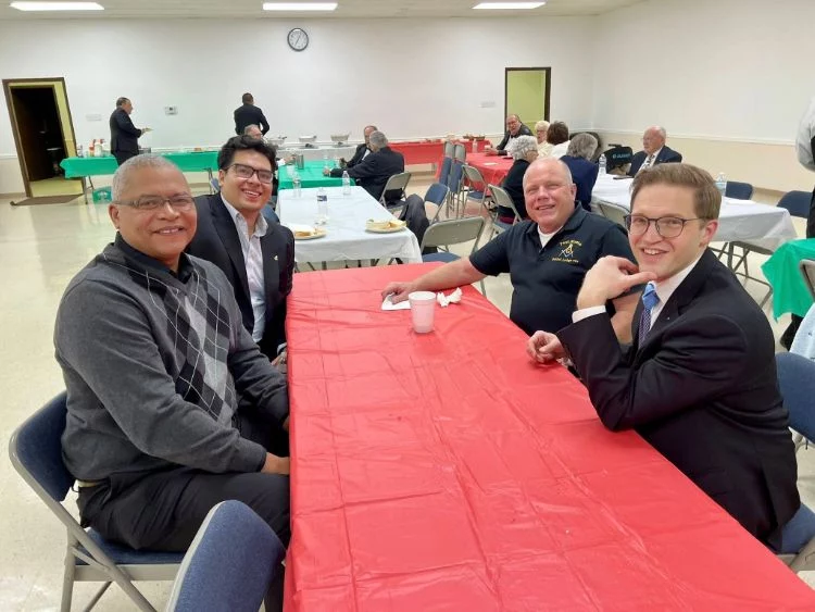 600174844_875325888408090_6798506056040663904_n Smiling group of four men seated at a table together.