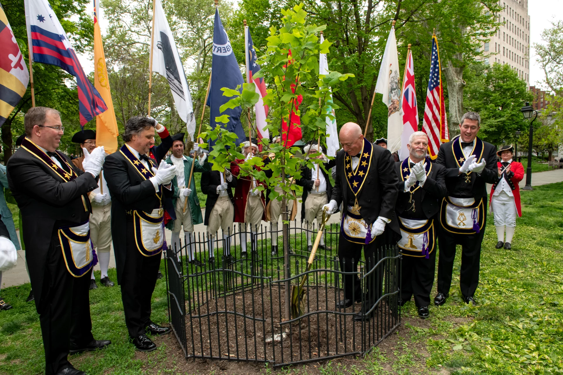 Grand Lodge Officers applauding as Grand Master Robert Brink helps plant a Liberty Tree in Philadelphia.