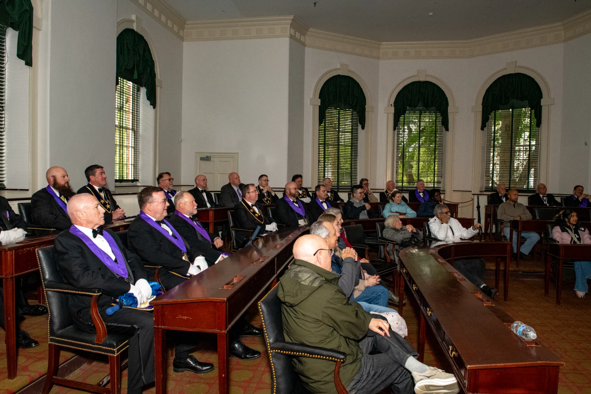 Group of Masons and their families seated at wooden desks.