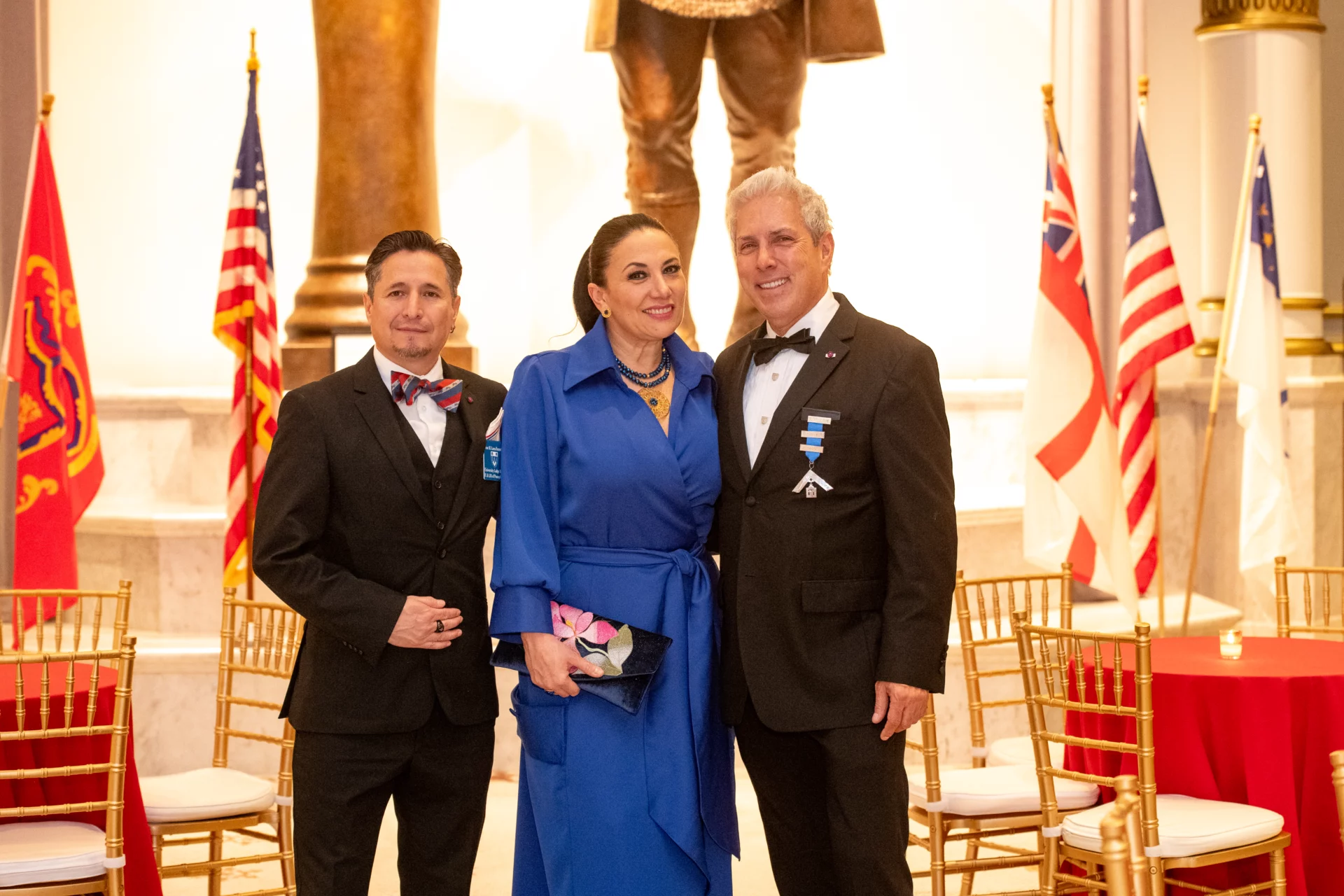 Smiling group of two men and one woman in formal attire.