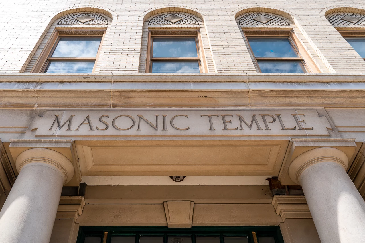 Front entrance of Masonic Temple, a light colored brick building with large windows and columns around the doorway.