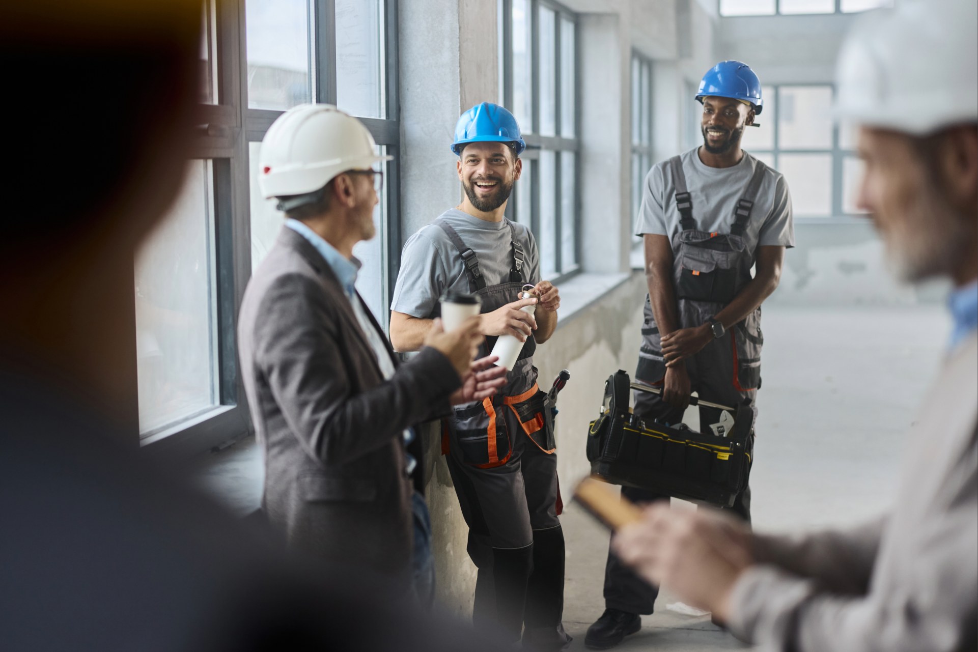 Smiling group of men in in hardhats standing in building.