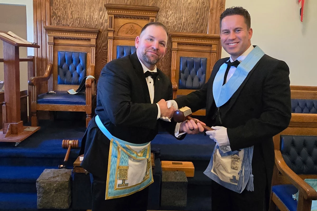 Smiling men shaking hands in a lodge room.