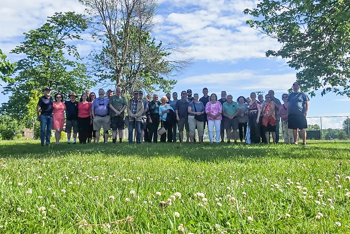 Smiling group of people standing in field outdoors.