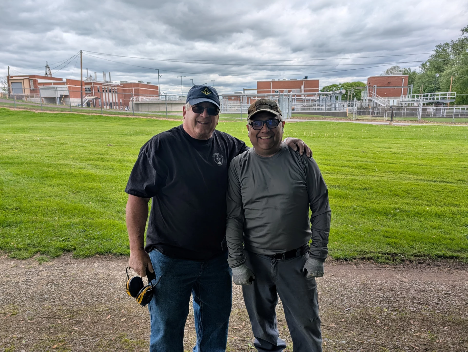 Two smiling men standing outdoors with arms around each other.