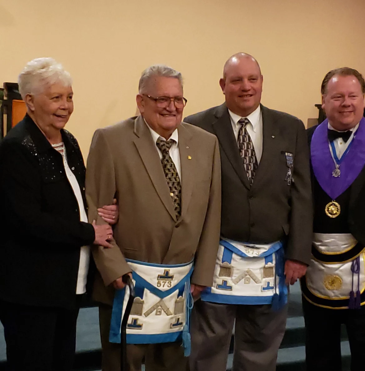 Smiling group of Masons, one standing with his partner, together indoors.